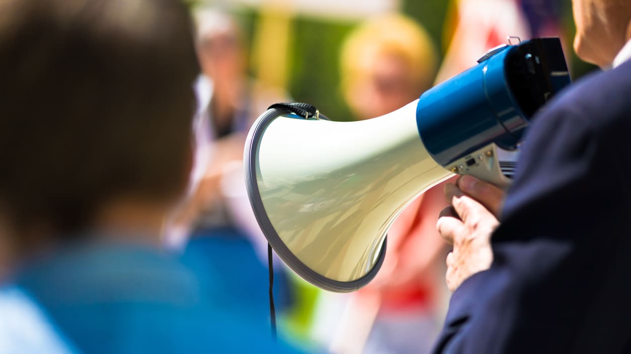 A man holding a megaphone in front of a crowd.