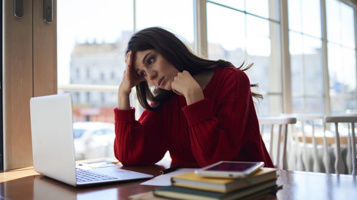 A woman sitting at a desk with a laptop in front of a window.