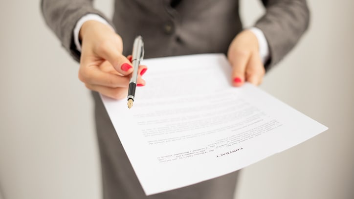 A business woman holding a document with a pen.