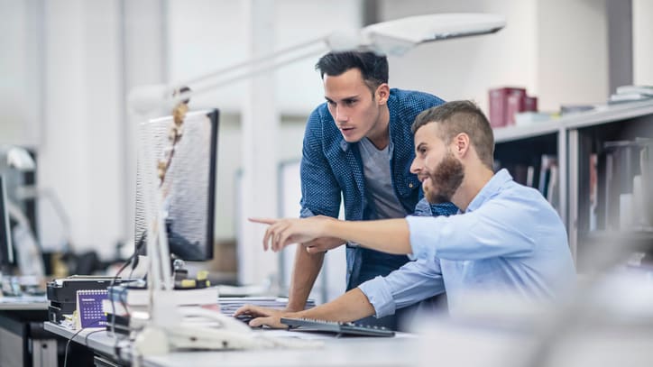 Two men working on a computer in an office.