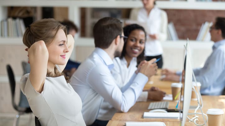 A group of people sitting at a desk in an office.