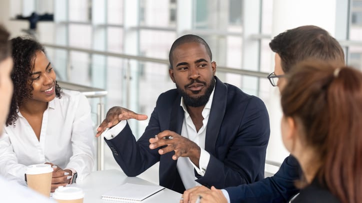 A group of business people sitting around a table in an office.