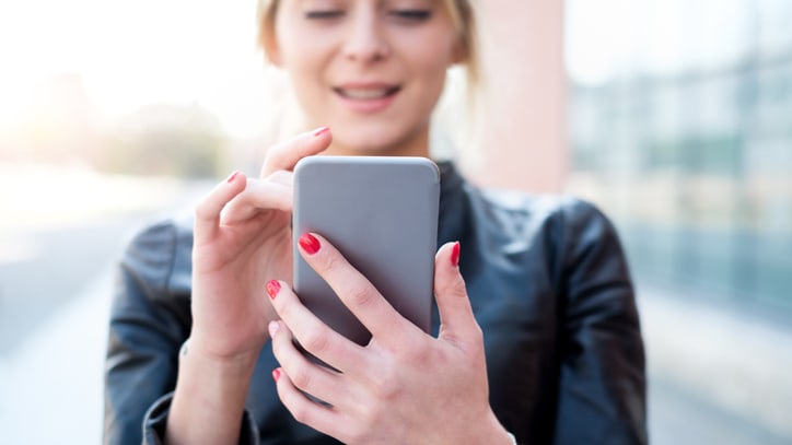 A woman is holding a cell phone in her hand.