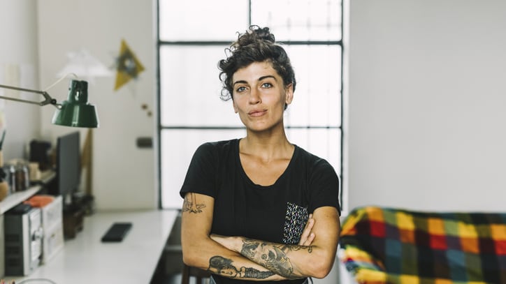 A woman with tattoos standing in her home office.