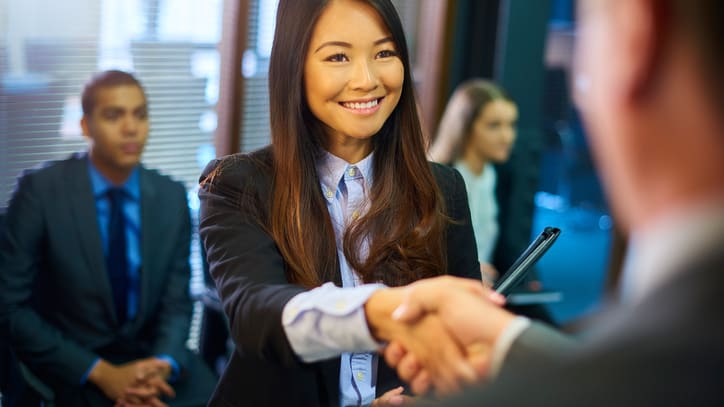 A businesswoman shaking hands with a group of people.