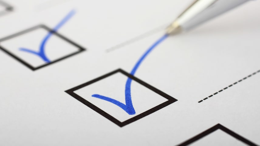 A blue pen is used to mark a check mark on a checklist.