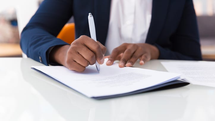 A business woman signing a document with a pen.