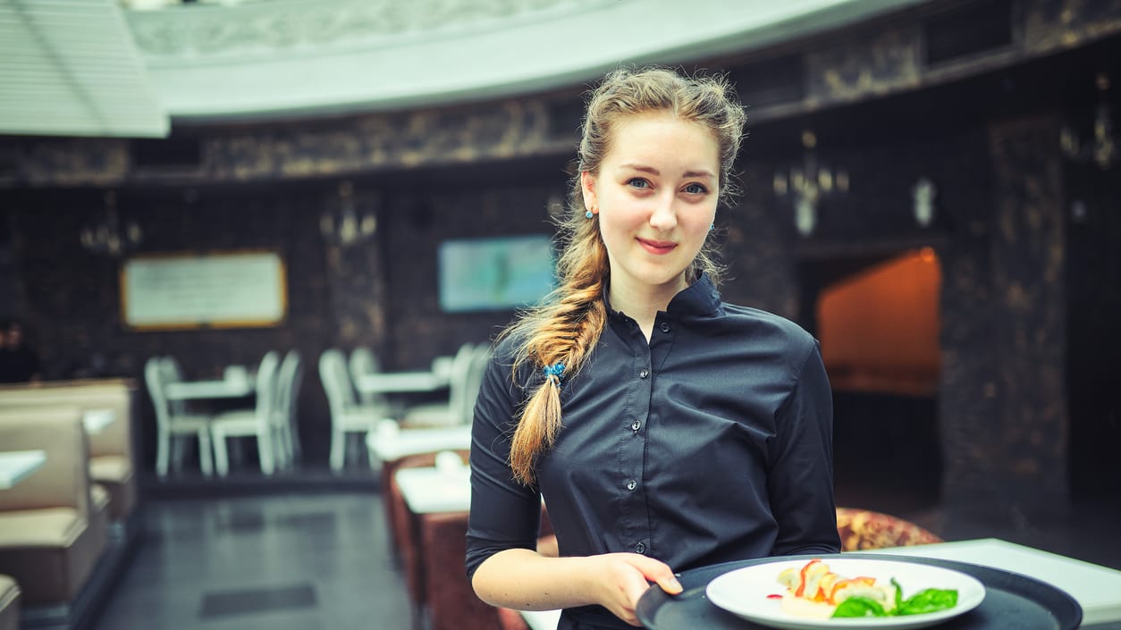A waitress holding a plate of food in a restaurant.