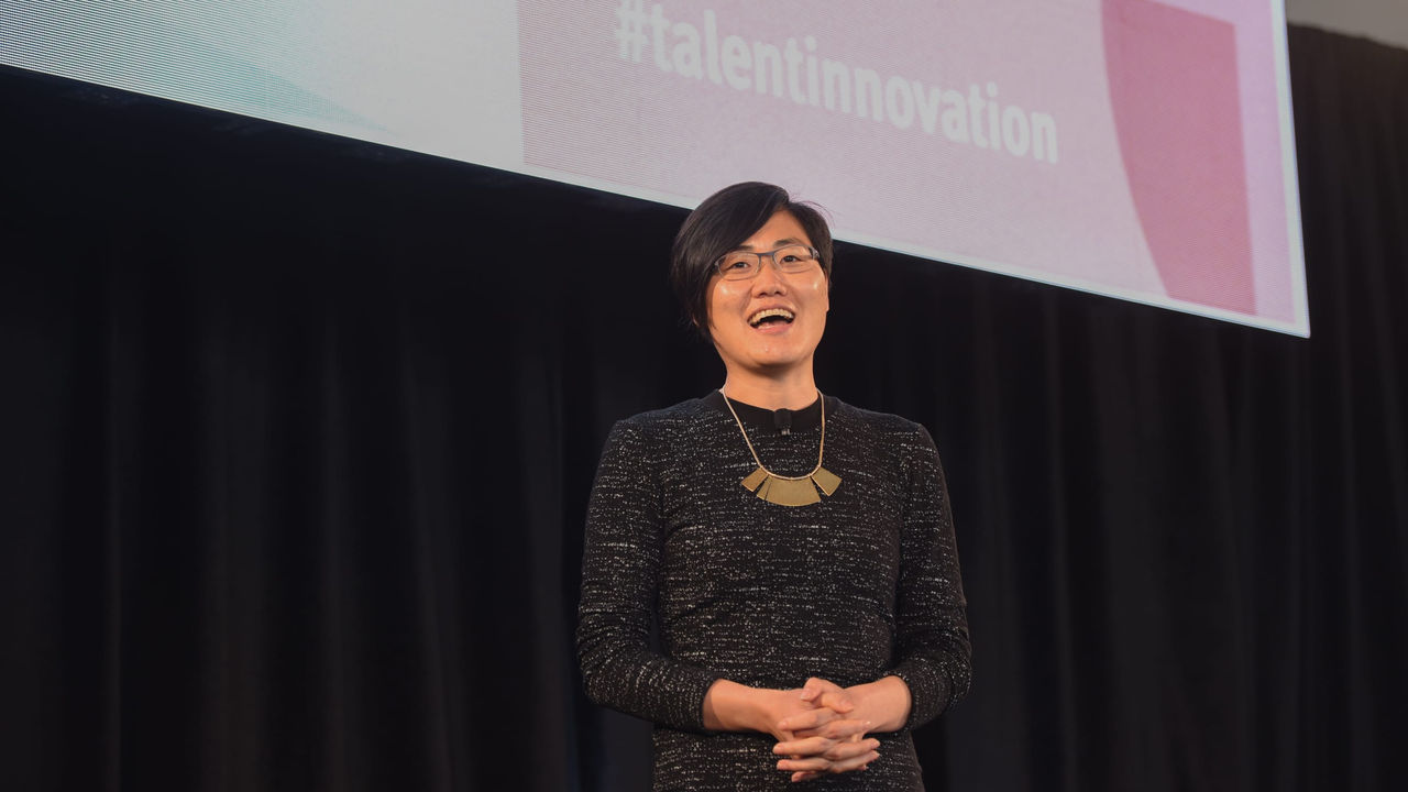A woman standing in front of a screen with the words talent innovation.