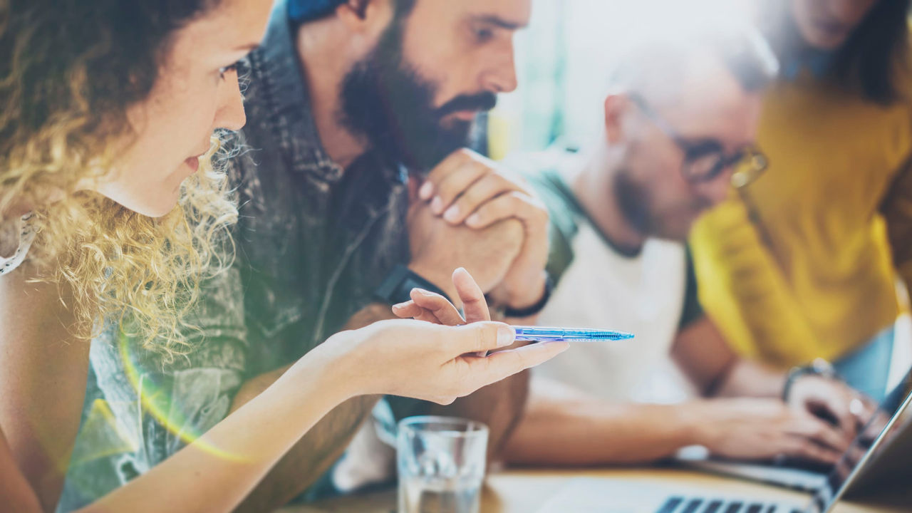 A group of people sitting around a table looking at a laptop.