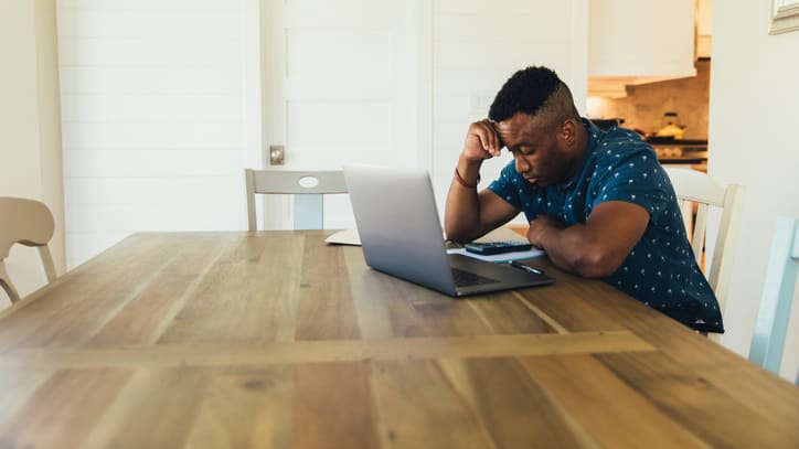 A man sitting at a table with a laptop.