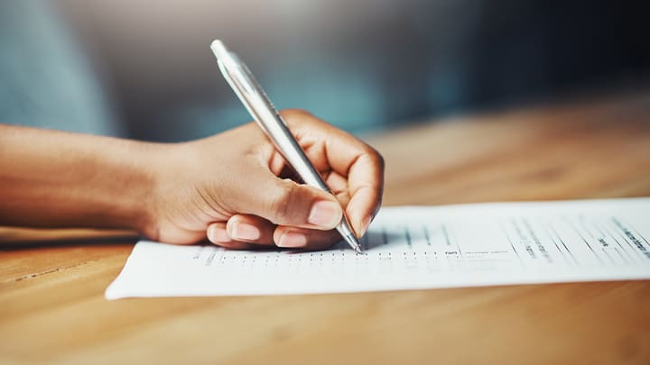 A person signing a document with a pen.