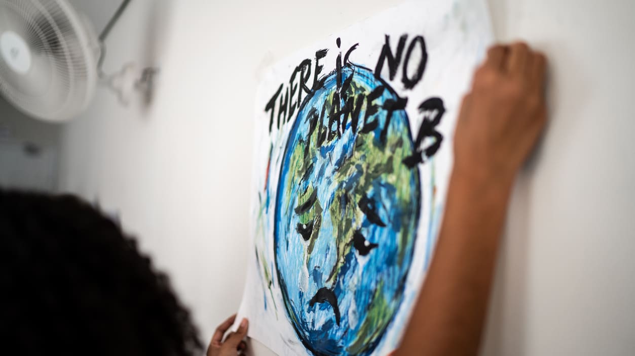 A woman is holding up a poster that says there's no planet b.