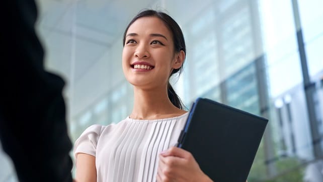 Businesswoman shaking hands with a man in front of a building.