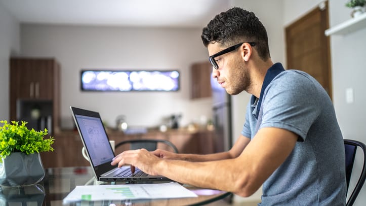 A man sitting at a table working on his laptop.