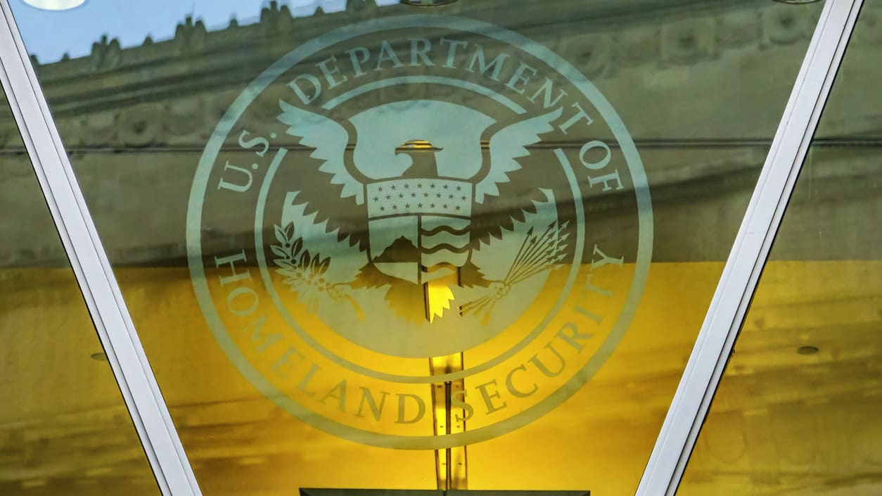 The u s department of homeland security logo is reflected in the glass of a building.