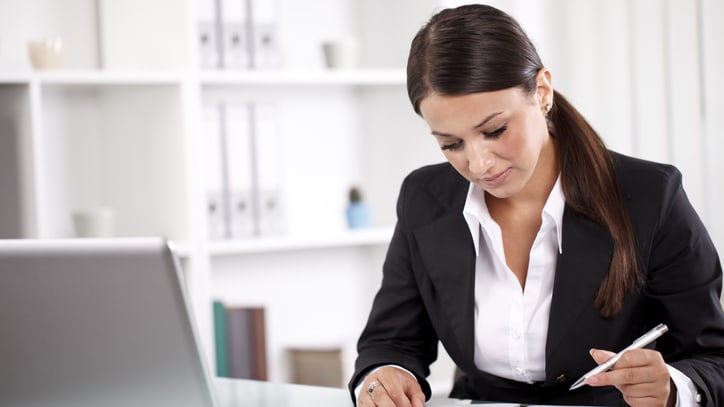 A woman in a business suit writing on a laptop.