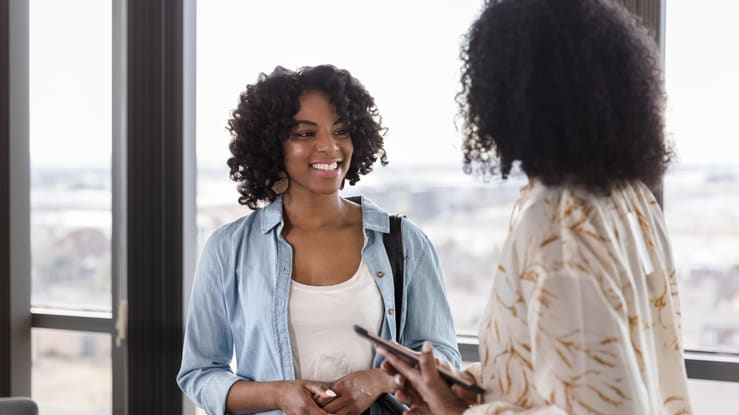 Two black women talking in an office.
