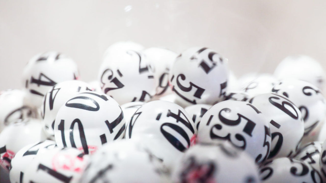 A bowl full of white and black balls with numbers on them.
