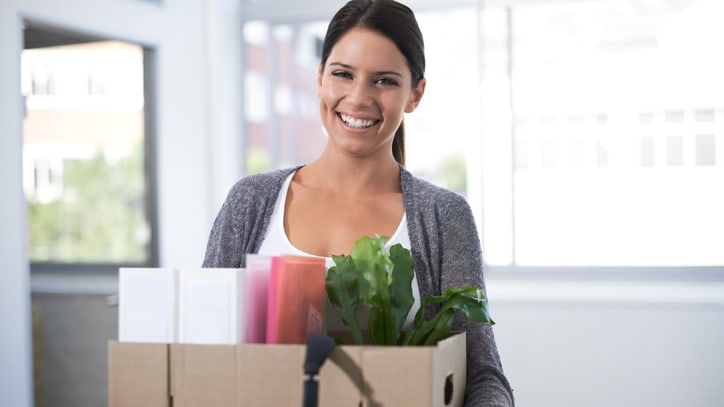A woman holding a cardboard box with plants in it.
