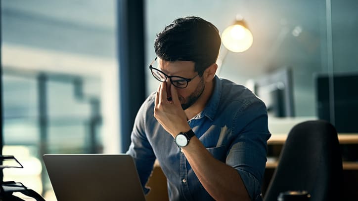 A man is sitting at a desk looking at his laptop.