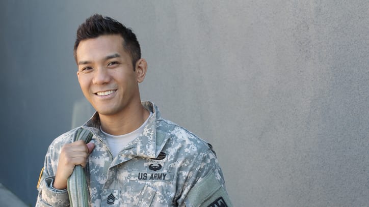 A young man in military uniform smiling.