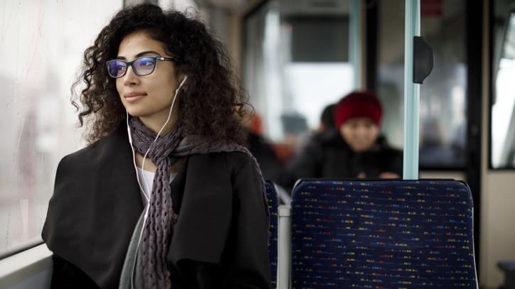 A woman wearing glasses is sitting on a bus.