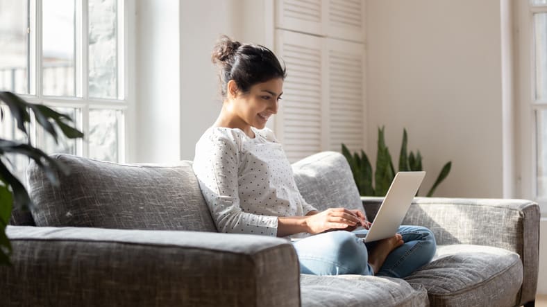 A woman sitting on a couch using a laptop.