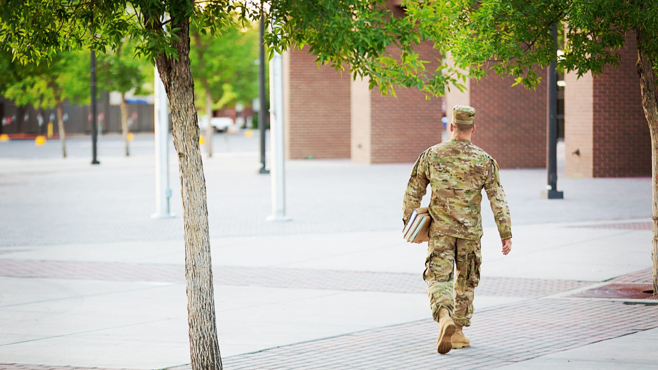 A man in a military uniform walking down a sidewalk.