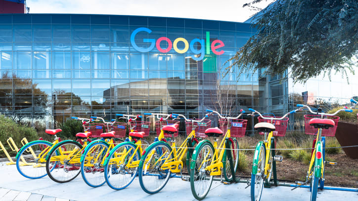 A group of bicycles parked in front of a google building.