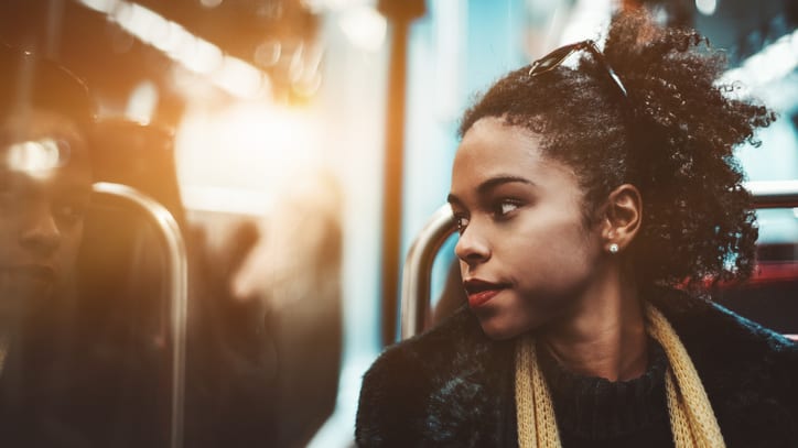 A woman on a train looking at her reflection.