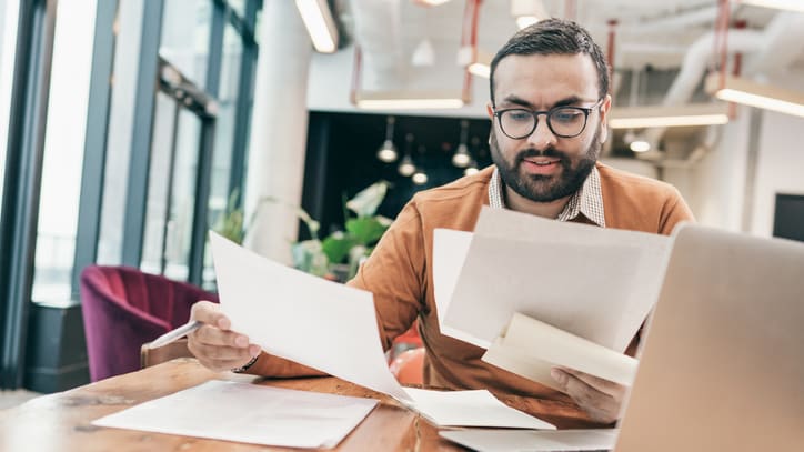 A man sitting at a table with papers and a laptop.