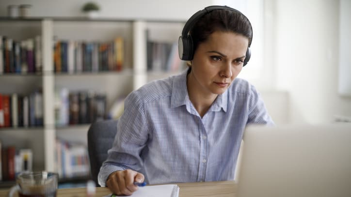 A woman wearing headphones at a desk with a laptop.