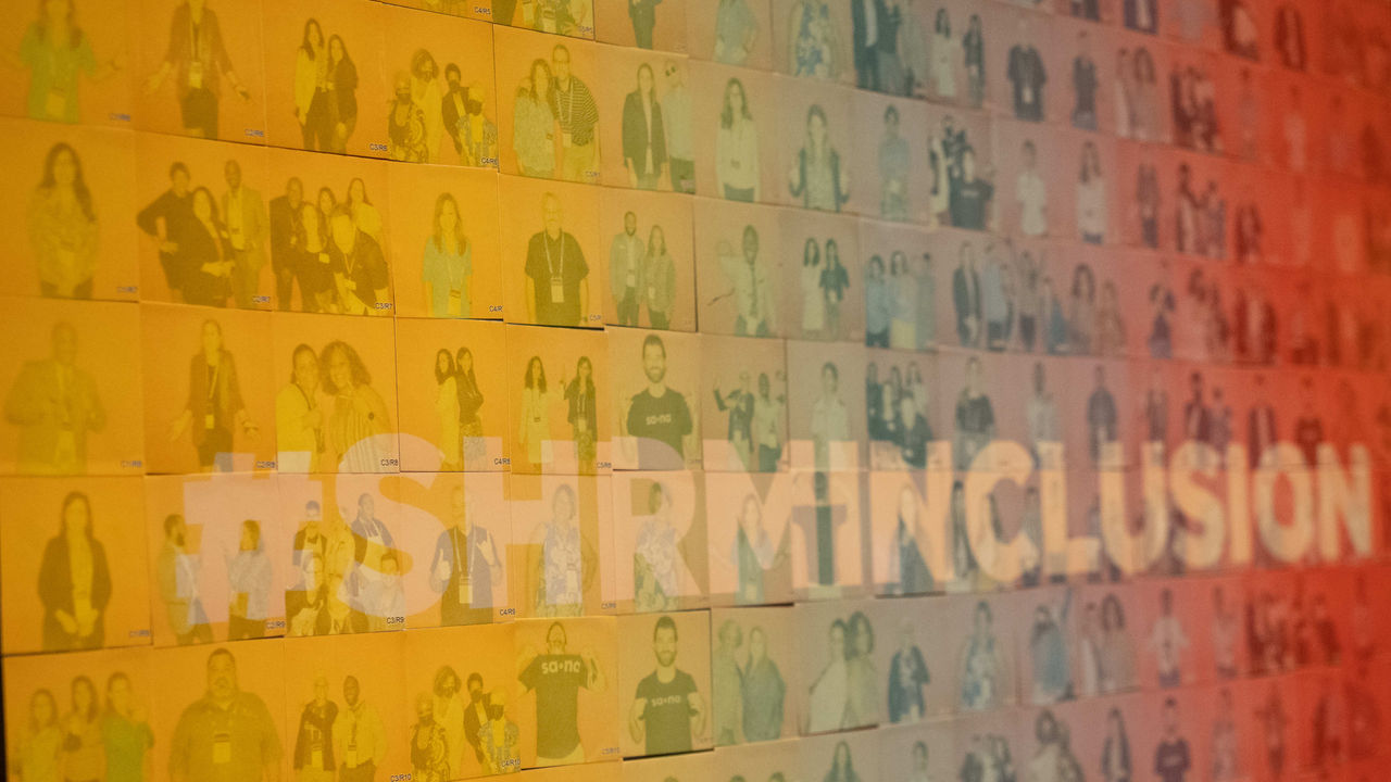 A group of people standing in front of a wall that says shrm inclusion.