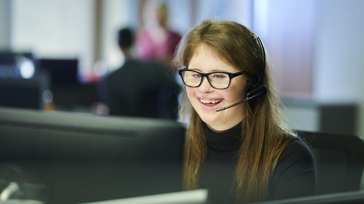 A woman wearing glasses and a headset in a call center.