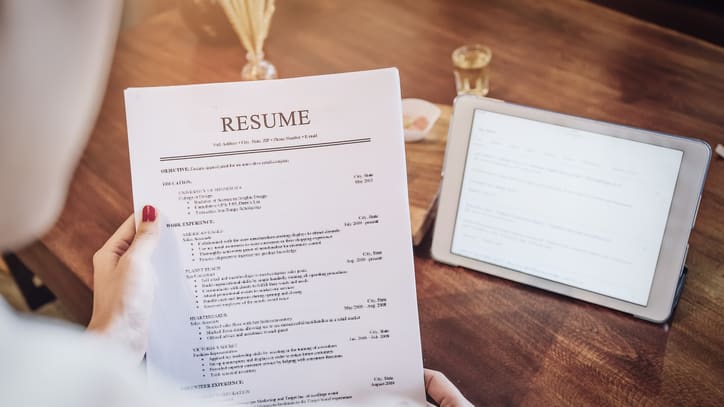 A woman is holding a resume on a table.