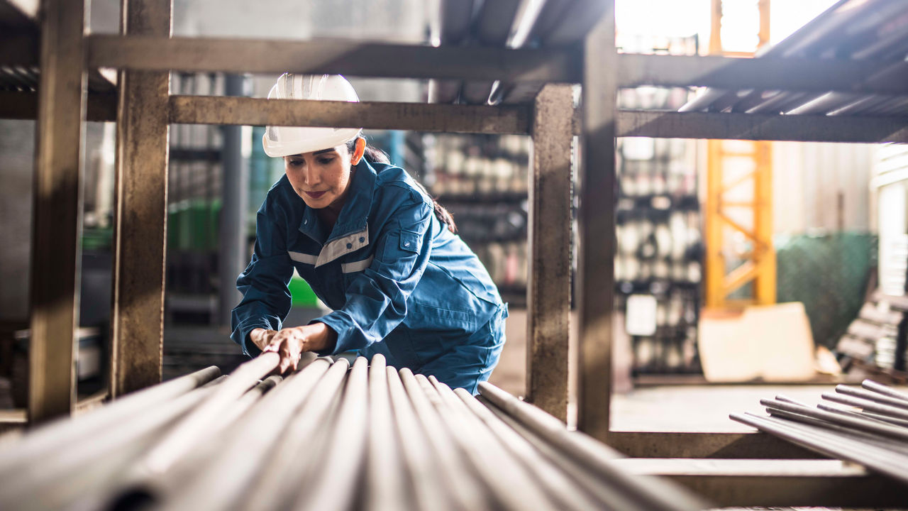 A worker is working in a factory with pipes.