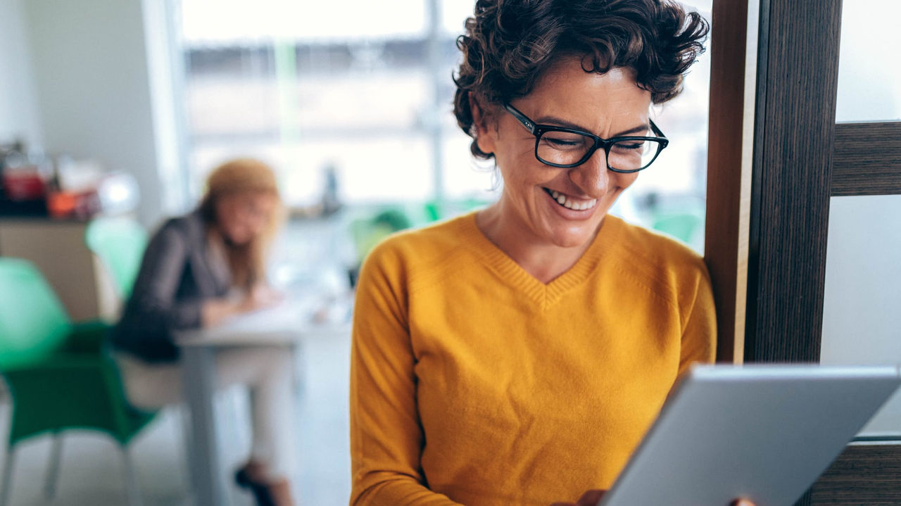 A woman smiling while holding a tablet.