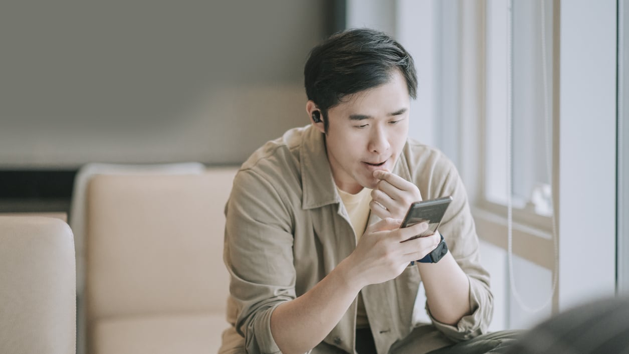 A man sitting on a couch looking at his phone.