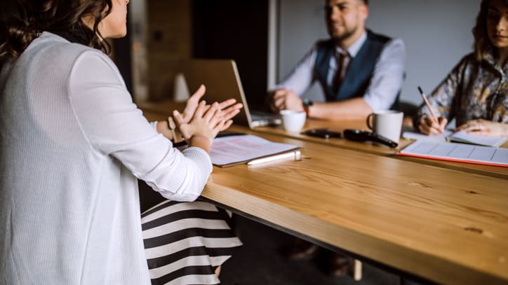 A group of people sitting around a table in a meeting.