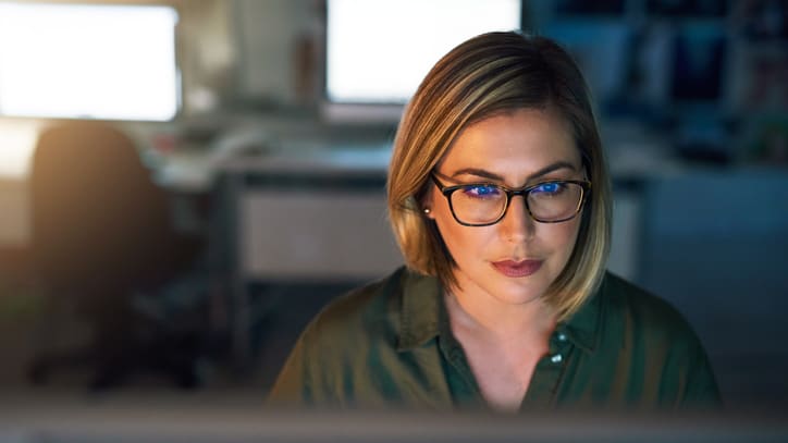 A woman wearing glasses is looking at a computer screen.