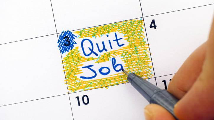 A person writing the word quit job on a calendar.