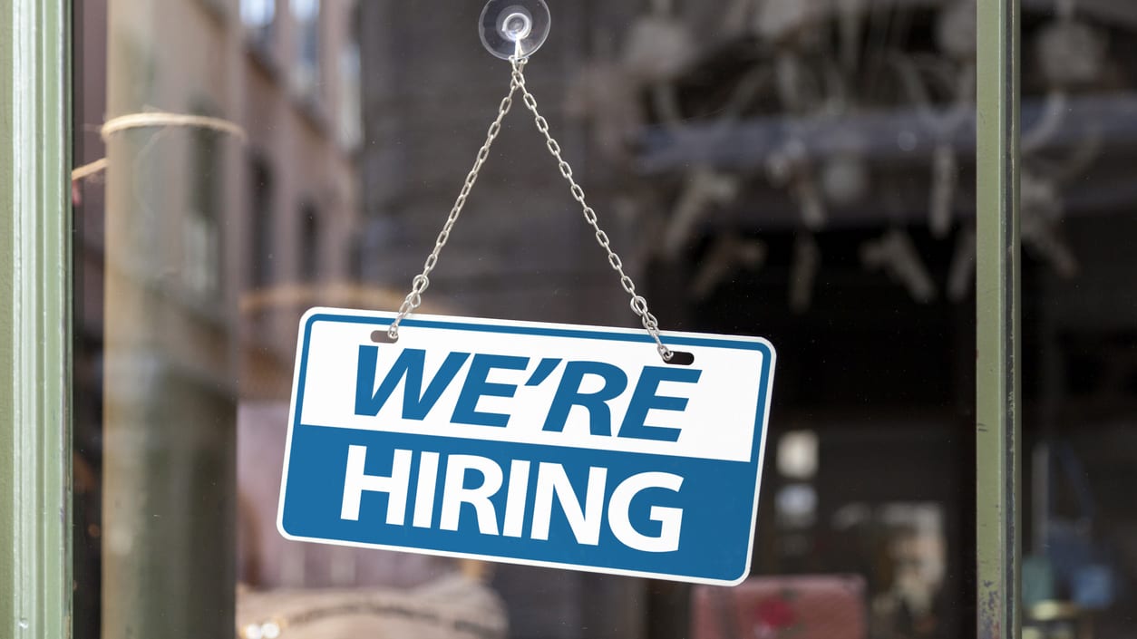 We are hiring sign hanging from a window.