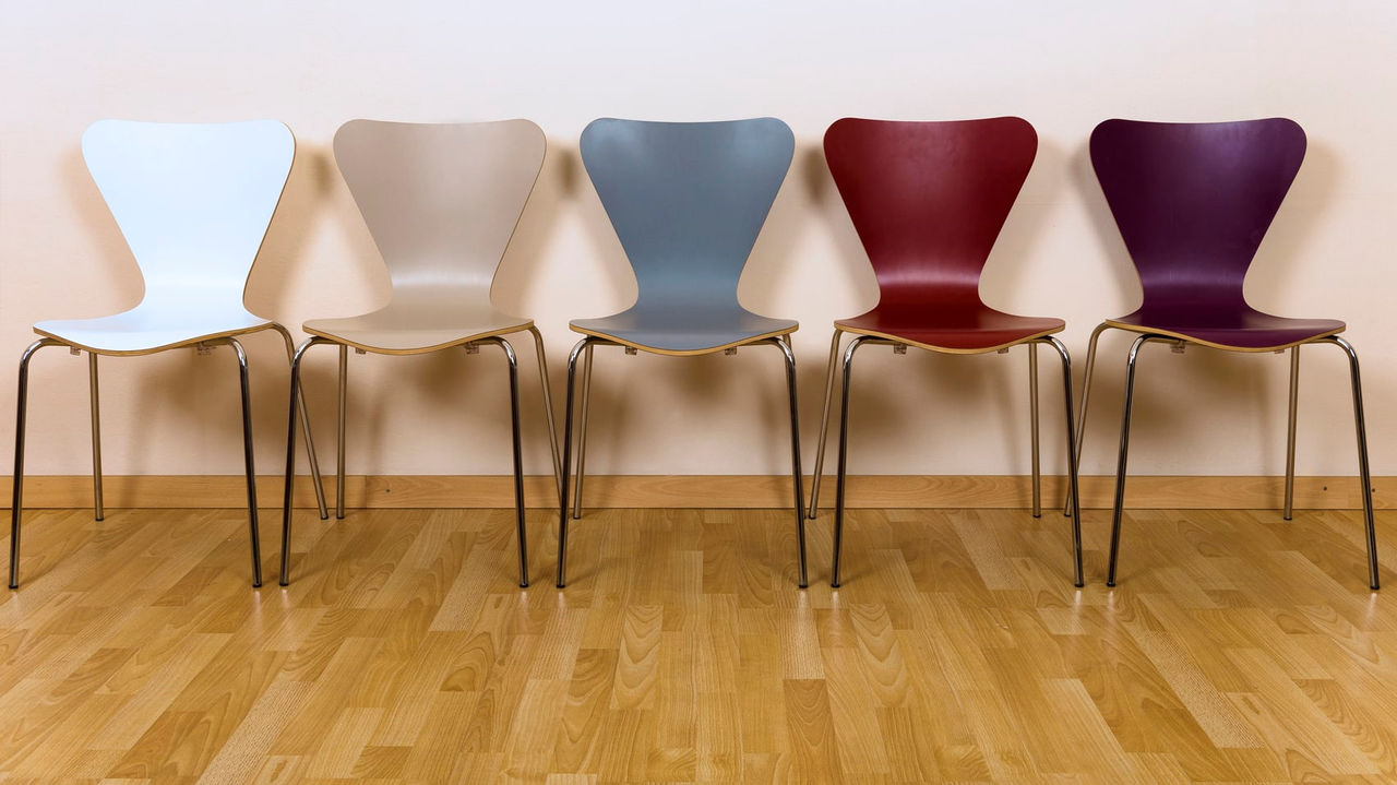 Five chairs in a row against a wall.