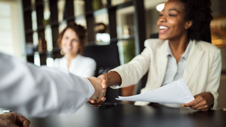 A woman shaking hands with a man in an office.