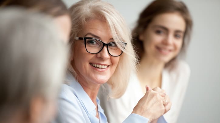 A group of women in glasses are sitting in a meeting.