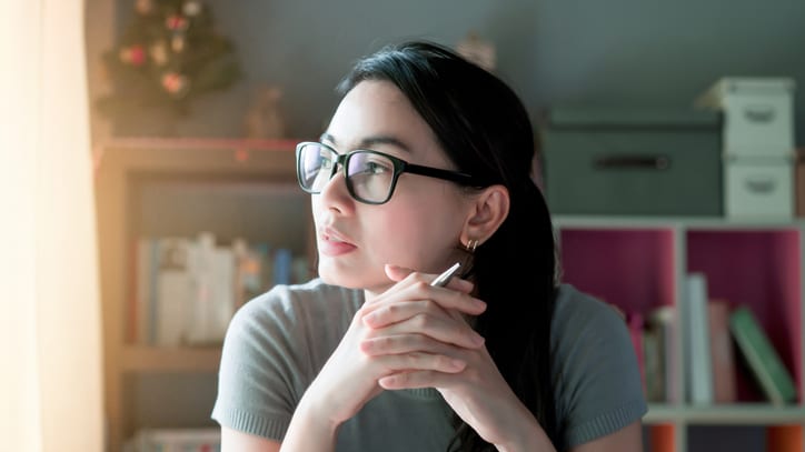 A woman in glasses is sitting in front of a laptop.