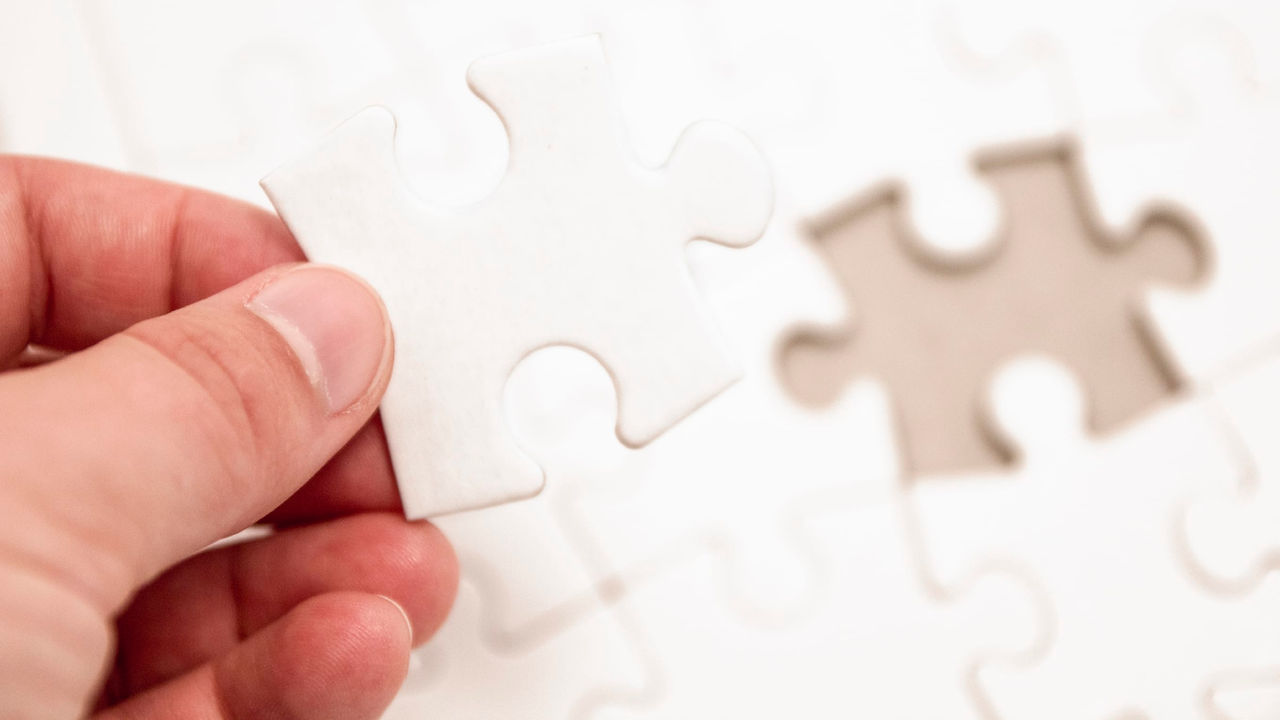 A person is holding a piece of a jigsaw puzzle.