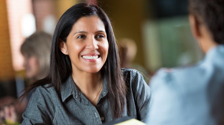 A woman smiling at a restaurant table.