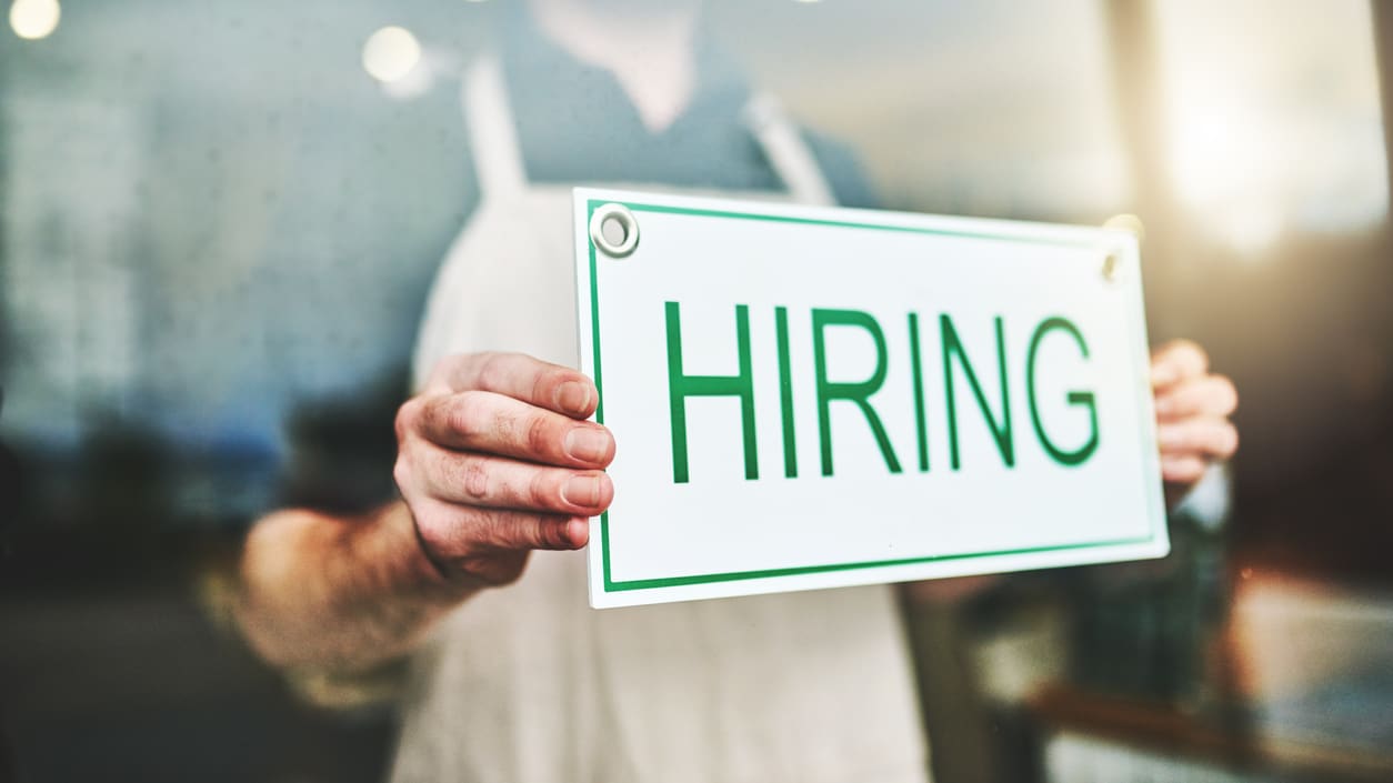 A man holding up a sign that says hiring.